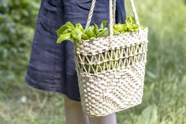 Bir kadın hasır hasır bir alışveriş çantası taşır..