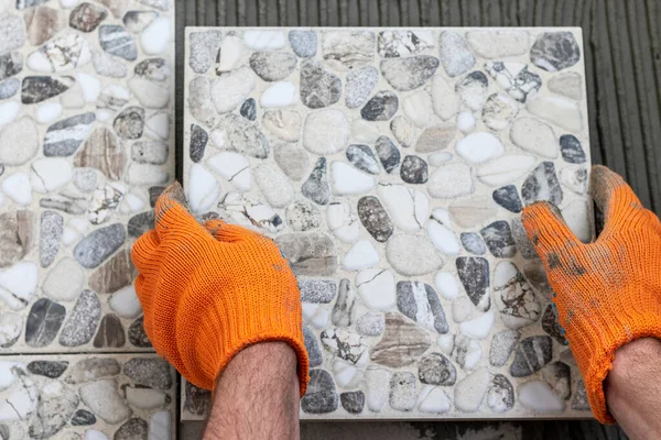 Male hands with tile and glue on wall. Work of laying tiles. Close up.