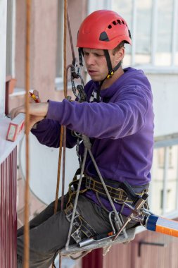Bir işçi, yüksek binadaki bir balkon seviyesini ölçer. Yüksek irtifa işe yarıyor. Endüstriyel dağcılık.