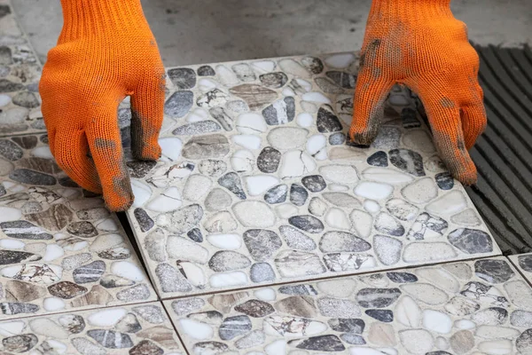 在地板上涂上胶水的瓷砖的工艺 工人的手与瓷砖紧密相连 — 图库照片