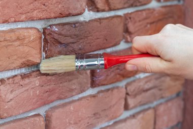 Alçıtaşı dekoratif tuğlalar arasındaki vernikleme işlemi. Duvarı su geçirmez kaplamayla örterek..
