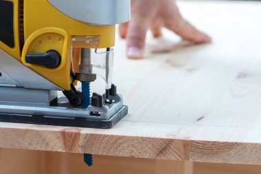 İşçi elektrikli bir yap-boz ile tahtayı keser. Kapat..