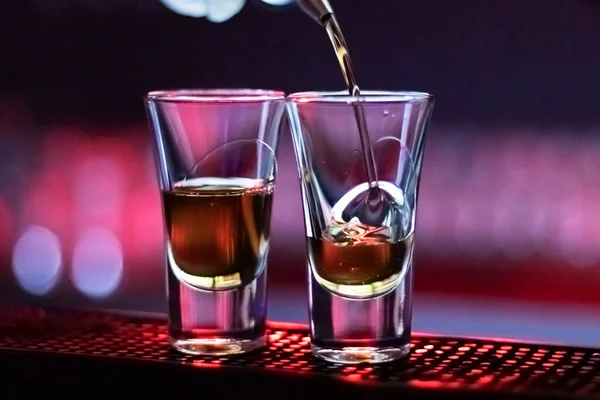 アルコールをグラスに注ぐ ナイトバーでのショートドリンク カラフルなネオンライト 暗い影 — ストック写真