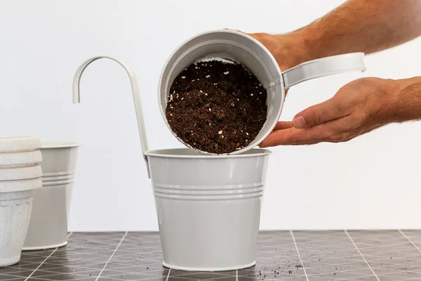 Man pours potting soil into pots for plants.