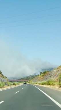 SALVATIERRA DE TORMES, İSPA - 16 Ağustos 2025: Extremadura, İspanya 'daki orman yangınlarından çıkan duman ve alevler, puslu bir gökyüzü altında yol kenarından çarpıcı bir şekilde görülebilir.