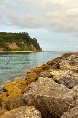 İspanya, Villaviciosa 'daki Rodiles Sahili, bulutlu hava altında yumuşak dalgalar, ıslak kum ve sakin, karamsar bir kıyı atmosferi var..