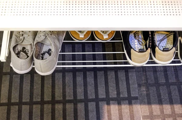 Sports shoes on a stand in the hallway. Sneakers for women and men.