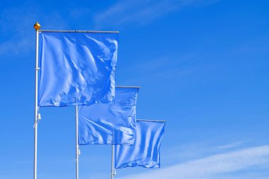 Mavi bayraklar bulutsuz gökyüzü karşı rüzgarda sallayarak. Herhangi bir logo, sembol veya işareti eklemek için mükemmel düzen.