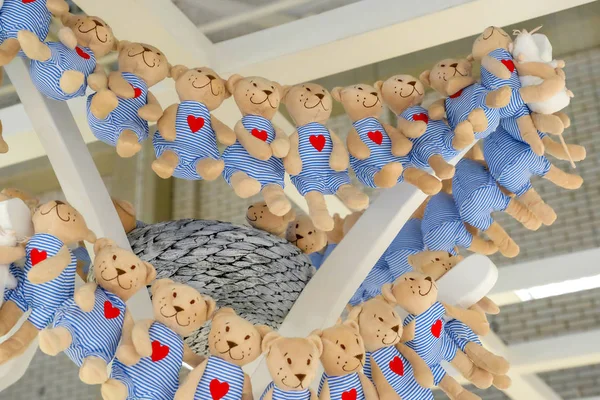 Lots of plush toys. Soft bear figures. In striped clothes. With a red heart on his chest.