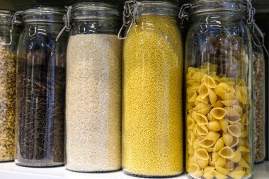 Çeşitli ham hububat ürünleri, tahıl, fasulye ve makarna mutfak raf, cam kavanozlara sağlıklı yemek pişirmek için arka plan beyaz. Temiz yemek, Vejeteryan, Vejeteryan, dengeli diyet gıda kavramı