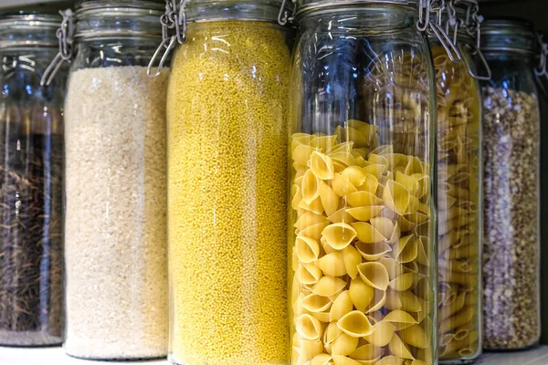各种生谷物 豆类和面食健康烹饪在厨房架子上的玻璃罐 白色的背景 干净的饮食 素食主义者 均衡的节食食品概念 — 图库照片