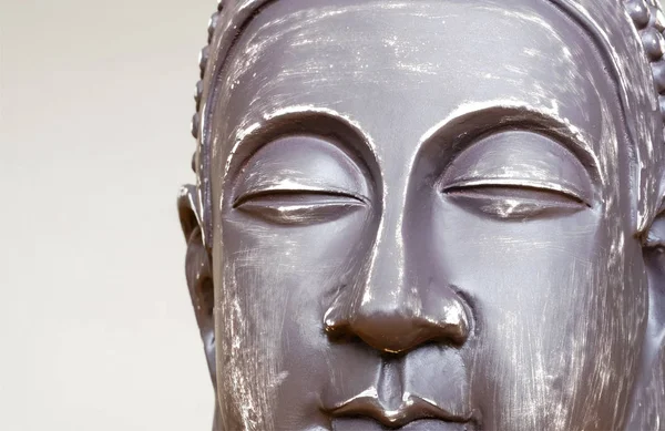 Buddha\'s face close-up. The Buddha image in ceramics. The texture of the background and focus of the soft focus. For an atmosphere of meditation.