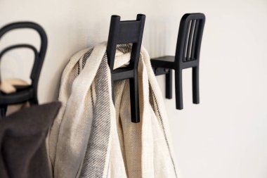 Kanca üzerinde beyaz bir duvar tasarlanmıştır. Oltaya bir eşarp kilitleniyor. Sandalye şeklinde duvara kanca. Olağandışı dekor.