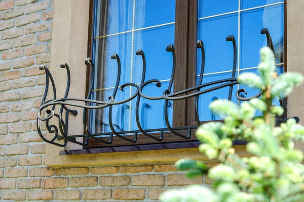 Brown window with stylized forged black iron bars