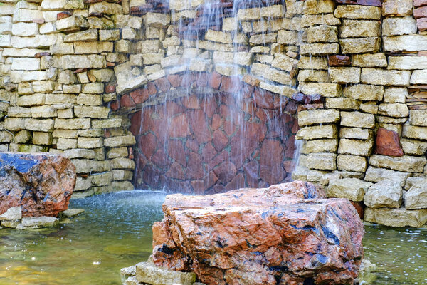 Waterfall in landscape design decorated with natural natural stone.