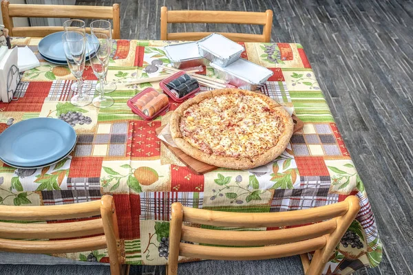 The composition on the cutting Board pizza and sushi for fast food. Wooden sticks for sushi. Fresh, hot and nutritious food.