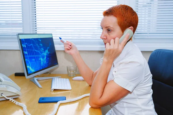 Beautiful girl stock broker talking on the phone in the office