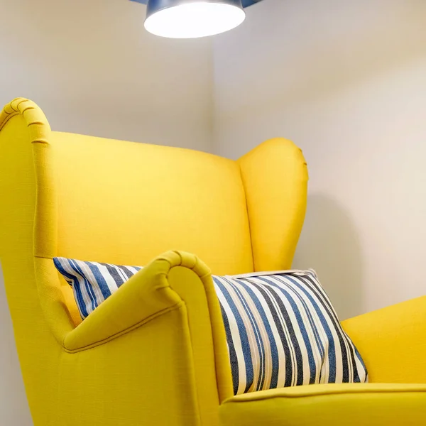 Cadeira amarela myagkoe com almofada, lâmpada de leitura traseira alta acima de sua cabeça . — Fotografia de Stock