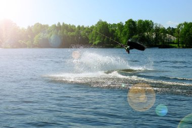 Atlet-wakeboarder havada bir atlama bir takla ile gerçekleştirir. Güneş ışığında.
