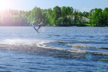 Atlet-wakeboarder havada bir atlama bir takla ile gerçekleştirir. Güneş ışığında.