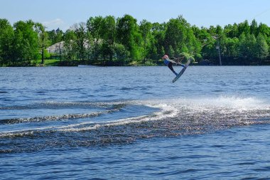 Atlet-wakeboarder havada bir atlama bir takla ile gerçekleştirir. Güneş ışığında.