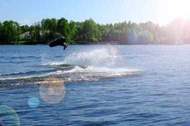Atlet-wakeboarder havada bir atlama bir takla ile gerçekleştirir. Güneş ışığında.