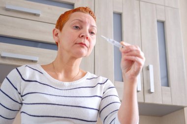 Kadın onun elinde bir termometre ile. Yüksek vücut sıcaklığı