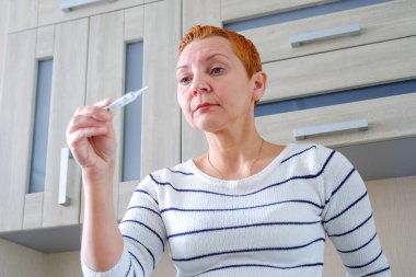Bir termometre, önlemler vücut ısısı, viral hastalıklar tutan kadın. Kadın onun elinde bir termometre ile. Yüksek vücut sıcaklığı