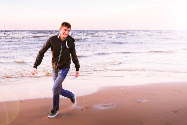 Mutlu genç adam bir kuş gibi uzanmış kolları sahilde duran mesafe içine seyir sıcak rüzgar duygu rahat ve kaygısız ücretsiz.