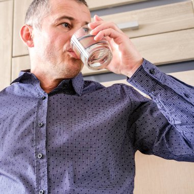 Bir adam migren uğrar. Bir baş ağrısı hap almaya devam. Bir bardak su tutar.