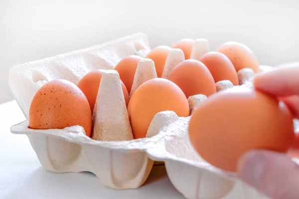 Chicken eggs on a tray. Selective focus. Chicken egg omelette for Breakfast. One egg in hand. Bokeh.