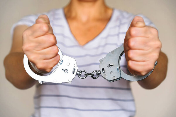 Задержанная женщина в полицейском участке. Наручники на запястьях задержанного
.