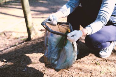 The girl collects garbage. Puts it in the garbage bag. The problem of environmental pollution. Ecological pollution. Problem of ecology.