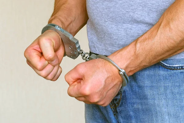 A man was detained in a police station. Handcuffs on the wrists of the detainee. Suppression of aggression. — Stock Photo, Image