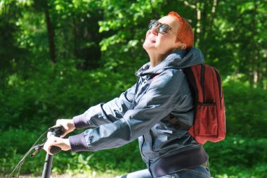 Kız mutlu gülümsüyor. Bisiklet yolu üzerinde Park sürme. Yüz güneş ışığına maruz.