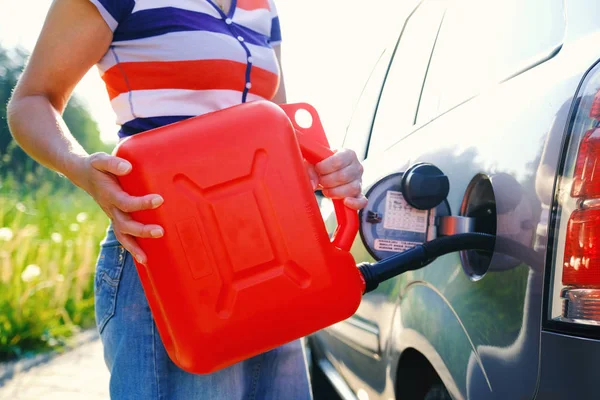 stock image A woman fills the car with gasoline from the spare tank. Canister of 10 liters.