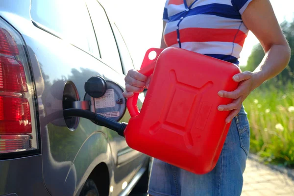 Zwangspause. Das Benzin im Tank des Autos ging aus. Eine Frau füllt das Auto mit Benzin aus einem Reservetank. Kanister mit 10 Litern. — Stockfoto