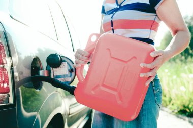 Zorla durma. Arabanın tankında benzin tükendi. Bir kadın arabayı yedek tanktan benzin ile doldurur. 10 litre teneke kutu.