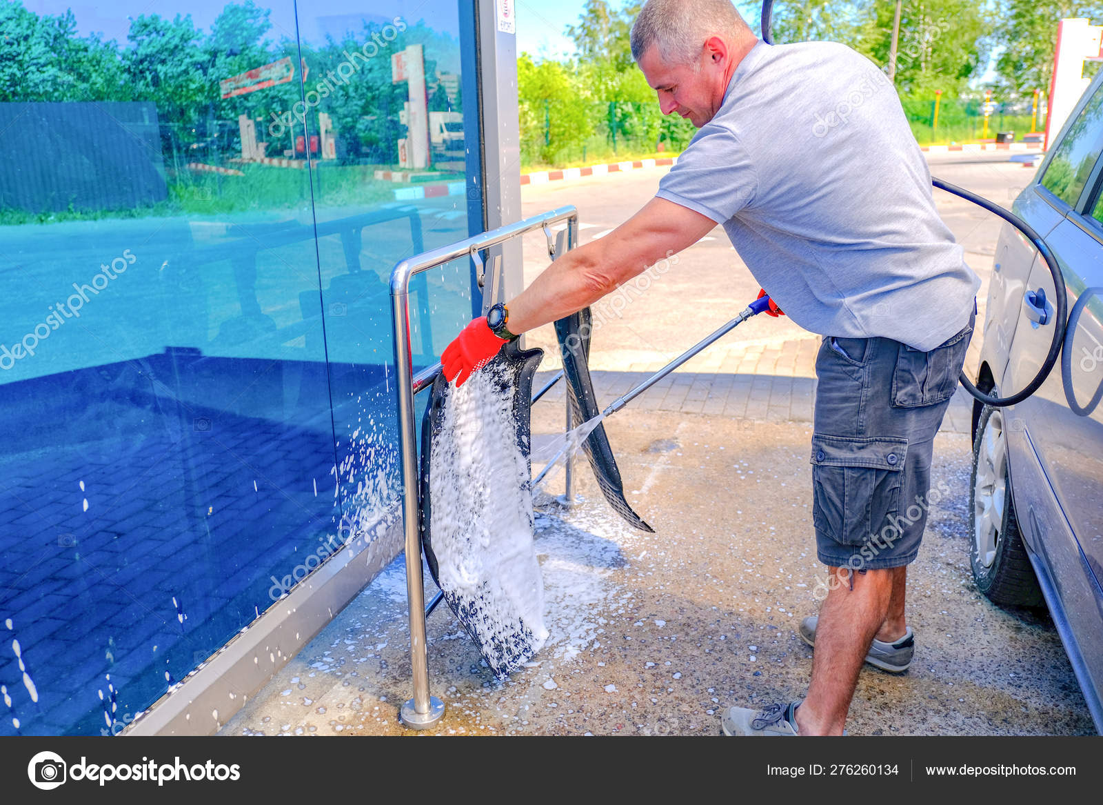 The man puts active foam on the car Mat. Car wash. Selfservice washing