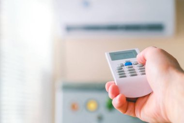 Uzaktan kumanda. Klima uzaktan kumandalı erkek eli. Adam klima modlarını değiştiriyor. Odanın soğutma sıcaklığını düzenler.