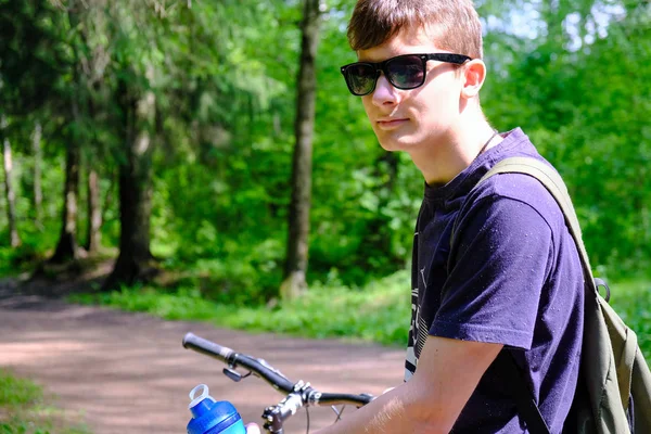 자전거 근처 산에 앉아 있는 청년. 그는 꿈꾸며 먼 곳을 바라본다. 스포츠 라이프스타일. — 스톡 사진