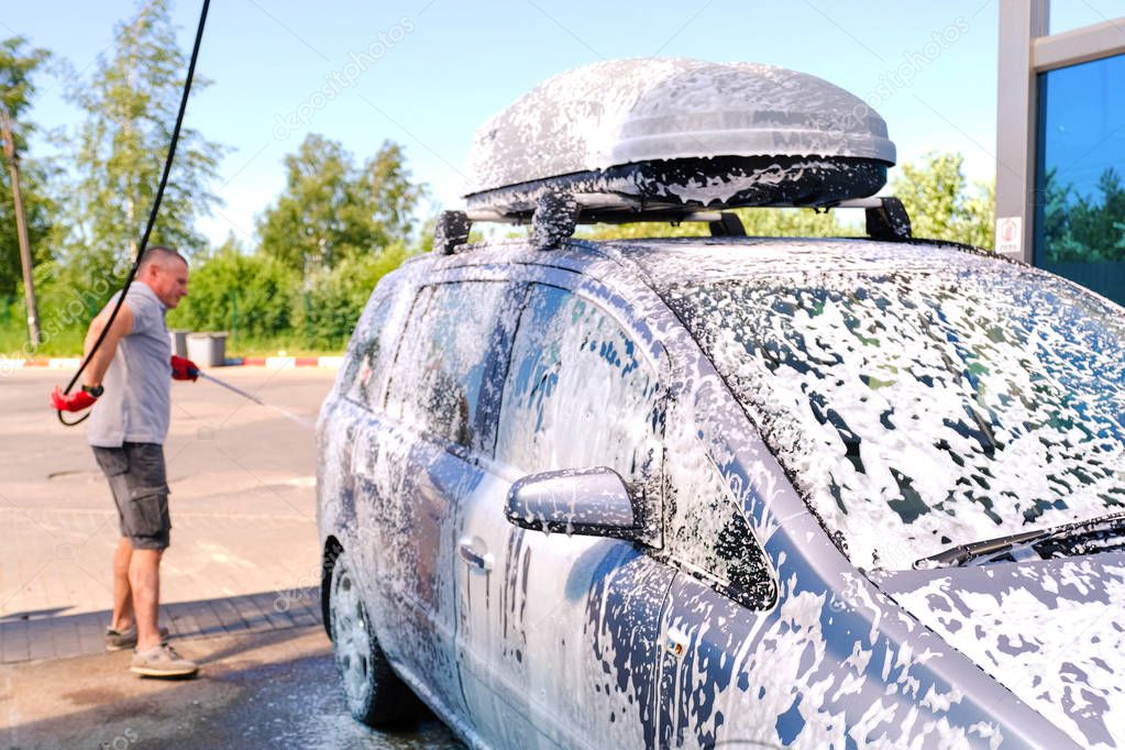 Man pours active foam car body. Car wash. Self-service washing complex. High pressure car wash.