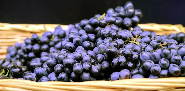 Ramas de uvas en una canasta de mimbre. Paquetes de uvas rojas maduras frescas en la tienda de comestibles, enfoque selectivo. Fondo de uva . — Foto de Stock