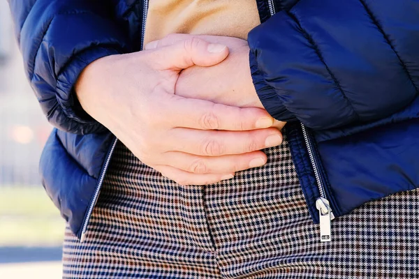 La chica en la calle sintió una punzada de dolor en su estómago. Aguantando con ambas manos hasta el punto dolorido. Ginecología para mujer . — Foto de Stock