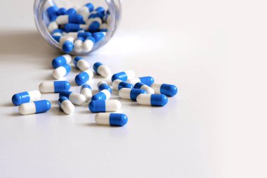 Kapsül şeklinde tabletler masanın üzerindeki bir kavanozdan yayılır. Yüksek çözünürlüklü fotoğraflar. Seçici odaklı makro fotoğrafçılık