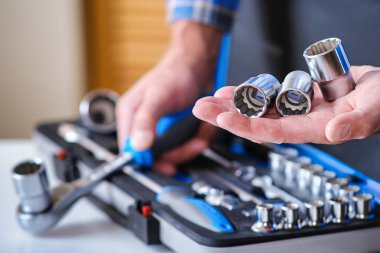 Bir çilingir elinde üç kafa, anahtarlar ve çıngırak. Anahtarları olan metal bir kutu. Kontrol edilmiş gömlekli bir çilingir elinde bir anahtar tutuyor.