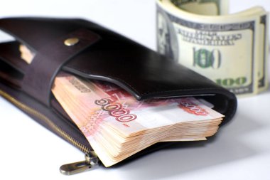 Deri bir cüzdanda bir tomar banknot. Yanında bir yığın yüz dolarlık banknot var..
