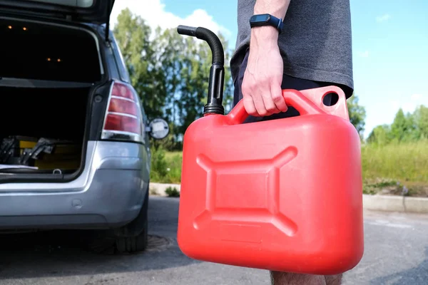 Kırmızı plastik bir gaz tüpü. Adam arabaya yakıt ikmali yapacak..