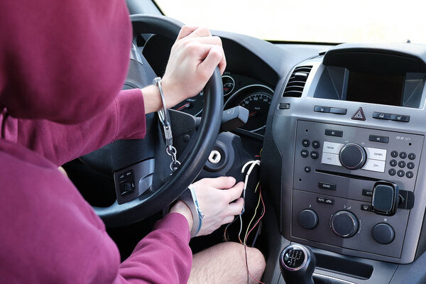 The criminal was caught stealing a car. The hijacker is handcuffed to the steering wheel. The police did a good job