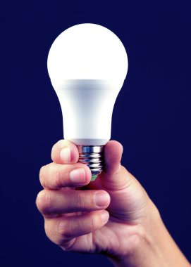 Bir insanın elinde enerji tasarrufu ampulü vardı. Modern ekonomik aydınlatma kavramı